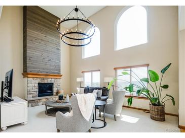 Bright living room features a fireplace, two-story ceilings, and updated modern lighting at 4320 Stone Post Dr, Castle Rock, CO 80108