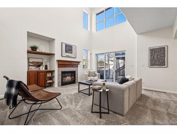 Bright living room with a cozy fireplace, high ceilings and sliding glass doors to the backyard at 12997 Wyandot Way, Westminster, CO 80234
