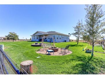 Spacious backyard featuring a fire pit, swing, and lush green grass with picturesque rural views at 11499 County Road 40 1/2 Rd, Platteville, CO 80651