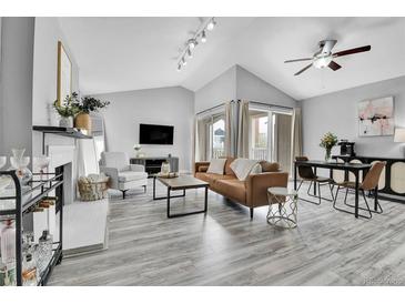 Bright living room with vaulted ceilings, modern furniture, fireplace, and sliding glass doors to a balcony at 3331 S Monaco Pkwy # C, Denver, CO 80222