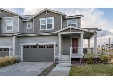 Charming townhome featuring a covered front porch, attached garage, and neutral gray siding at 9590 Sedalia St, Commerce City, CO 80022