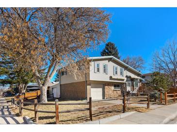 Charming split-level home boasts lovely curb appeal with mature trees and partial brick facade at 8721 E Cornell Dr, Denver, CO 80231