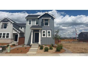 Charming two-story home with gray siding and white trim, complemented by fresh landscaping at 2087 Generations Aly, Brighton, CO 80601