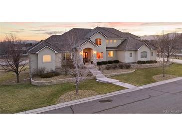 Stunning stucco home boasts a beautifully landscaped front yard and inviting arched entryway at 16394 W 77Th Ln, Arvada, CO 80007