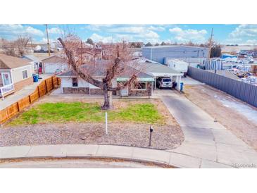 Charming single-story home with a spacious front yard and long driveway to a covered parking area at 5360 Monaco St, Commerce City, CO 80022