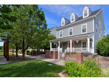 Charming two-story home boasts a classic gray exterior, inviting front porch, manicured lawn, and well-kept landscaping at 8171 E 33Rd Ave, Denver, CO 80238
