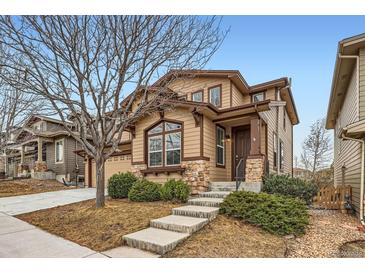 Charming two-story home with beige siding, brown trim, and stone accents on the facade, with concrete steps leading to the front door at 10677 Cedarcrest Cir, Highlands Ranch, CO 80130
