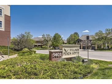 Eye-level sign reading '5401 Village Plaza Lofts' with mature landscaping and residential buildings in the background on a sunny day at 5401 S Park Terrace Ave # 109A, Greenwood Village, CO 80111