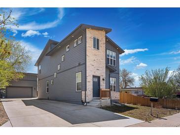 Modern two-story home featuring gray siding, stone accents, and a well-manicured front yard with a long driveway at 5470 Krameria St, Commerce City, CO 80022