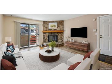 Inviting living room with a stone fireplace and sliding glass door to a private patio at 7720 W 87Th Dr # J, Arvada, CO 80005