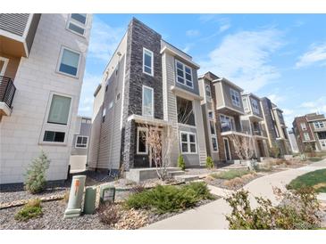 Modern townhome with gray siding, stone accents, and landscaped front yard at 11918 Mountview Ln, Broomfield, CO 80021