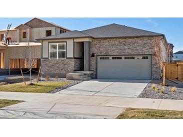 Beautiful single-Gathering home with stone accents, a gray roof, attached two-car garage, and newly installed front yard at 6050 Hourglass Dr, Brighton, CO 80601