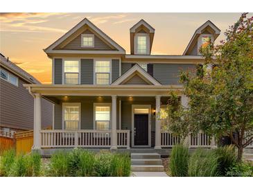 Inviting two-story home featuring a charming front porch, neutral siding, and lush landscaping at 14065 Harrison St, Thornton, CO 80602