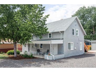 Charming gray two-story home featuring a covered front porch and mature landscaping at 2565 Pierce St, Lakewood, CO 80214