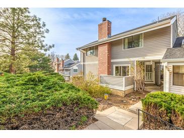Charming home featuring a brick chimney, gray siding, and lush landscaping at 93 S Nome St, Aurora, CO 80012