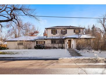 Two-story house with snow-covered lawn, a walkway, and mature trees at 6600 E 8Th Ave, Denver, CO 80220