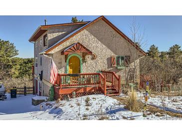 Charming stucco home with unique details, a red deck, and snowy landscape at 347 Buena Vista, Palmer Lake, CO 80133