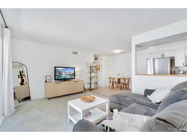 Bright living room featuring neutral decor, a comfortable grey couch, and an adjacent dining area at 9255 E Lehigh Ave # 208, Denver, CO 80237