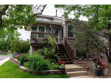 Charming home featuring a cozy front porch, brick accents, and lush landscaping with colorful flowers at 1470 S Quebec Way # 245, Denver, CO 80231