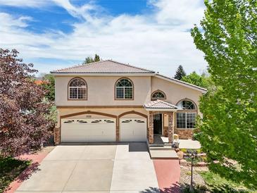 Charming two-story home showcasing a well-manicured lawn, a three-car garage, and beautiful arched windows under a bright sky at 4520 Maroon Cir, Broomfield, CO 80023