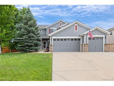 Charming two-story home with a three-car garage, lush green lawn, and mature landscaping at 11870 Cattle Ln, Parker, CO 80134