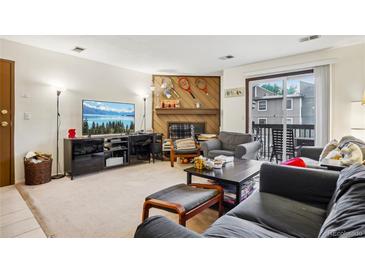 Comfortable living room featuring a decorative fireplace, sliding glass doors to balcony, and entertainment center at 2900 Shadow Creek Dr # 201, Boulder, CO 80303
