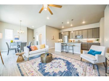 Open-concept living room featuring hardwood floors, stylish decor, and seamless flow into kitchen and dining area at 12574 Lake View St, Longmont, CO 80504