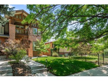 Beautiful brick home featuring a manicured lawn, lush landscaping, and charming curb appeal at 1934 S Sherman St, Denver, CO 80210