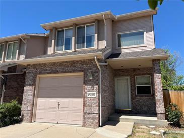 Charming two-story townhome with brick facade, attached garage, and well-maintained landscaping under a clear blue sky at 2035 Overland Dr, Brighton, CO 80601