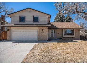 Charming brick and siding home featuring an attached garage, mature trees, and well-maintained lawn at 6527 S Ammons Ct, Littleton, CO 80123