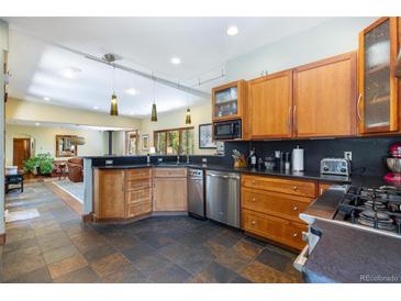 A spacious kitchen with stainless steel appliances, wooden cabinets, and a dark countertop that opens to living room at 167 Independence Cir, Breckenridge, CO 80424