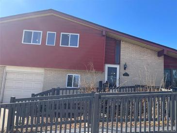 Two-story home featuring a combination of brick and red siding and a wheelchair ramp at 1473 S Monaco S Pkwy, Denver, CO 80224