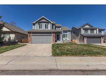 Charming two-story home with gray siding, brick accents, a well-manicured lawn, and an attached two-car garage at 8888 S Dudley St, Littleton, CO 80128