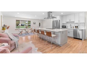 Modern open kitchen with stainless steel appliances, white cabinetry, and a large center island with bar seating at 1568 S Dudley Ct, Lakewood, CO 80232