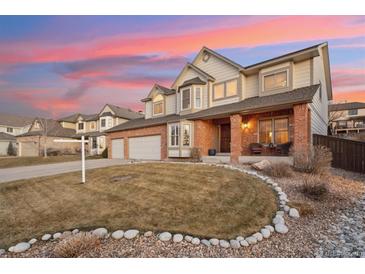 Inviting two-story home featuring a brick facade, well-manicured lawn, and a cozy front porch perfect for relaxing at 9407 Dolton Way, Highlands Ranch, CO 80126