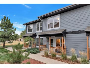 Charming gray two-story home with inviting porch, featuring wood railing and well-maintained landscaping, under a clear blue sky at 1457 S Pierce St, Lakewood, CO 80232