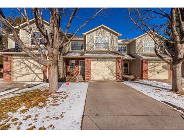 Tan two-story townhome with attached garage and snowy front yard at 15907 E 13Th Ave, Aurora, CO 80011