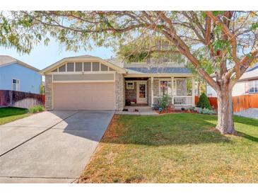 Charming home featuring a stone facade, two-car garage, inviting front porch and a well-manicured lawn at 16553 Gilpin St, Thornton, CO 80602