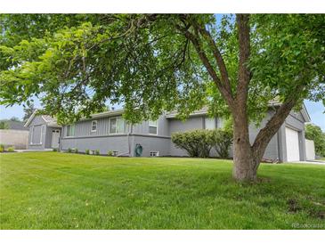 Charming single-story home with a well-maintained lawn and mature tree providing shade at 7155 E Exposition Ave, Denver, CO 80224