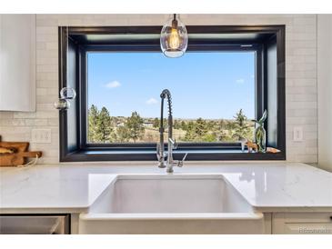 Bright kitchen featuring white countertops, farmhouse sink, subway tile backsplash, and a beautiful view at 7388 S Ireland Cir, Centennial, CO 80016