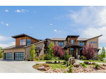 Stunning custom home with stone accents, modern design, lush landscaping, and a three-car garage at 2466 Spruce Meadows Dr, Broomfield, CO 80023