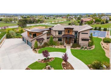 Beautiful exterior of a modern home with a basketball court, lush green lawn, and a three-car garage at 2466 Spruce Meadows Dr, Broomfield, CO 80023