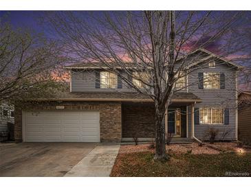 Charming two-story home featuring brick accents, blue shutters, and a well-maintained front yard with mature trees at 613 Rio Rancho Way, Brighton, CO 80601