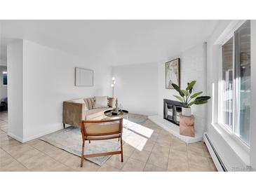 Bright living room with a white brick fireplace, neutral decor and tiled floors at 2700 S Holly St # 107, Denver, CO 80222