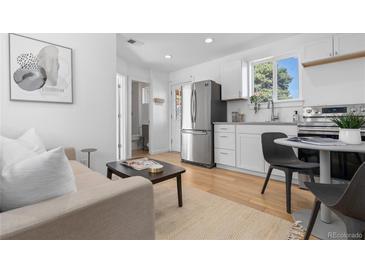 Bright living space flows to a modern kitchen featuring stainless steel appliances and a breakfast nook at 3903 W Nevada Pl, Denver, CO 80219