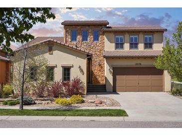 Charming two-story home featuring a stone facade and a well-manicured front yard with colorful landscaping at 15179 W Washburn Ave, Lakewood, CO 80228