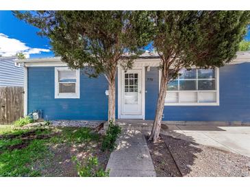 Charming blue home with a well-manicured front yard and white door, framed by mature trees at 770 Havana St, Aurora, CO 80010