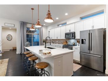 Modern kitchen with a large island, stainless steel appliances, and stylish lighting fixtures at 2572 Iola St, Aurora, CO 80010