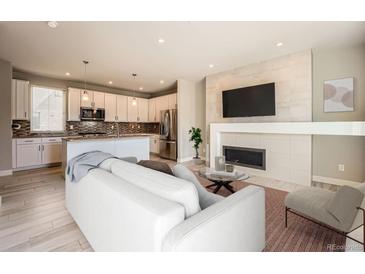 Open-concept living room features a fireplace, a mounted TV, and seamless flow into the kitchen at 701 E 24Th Ave, Denver, CO 80205