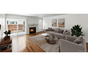 Bright living room with a fireplace, hardwood floors and sliding door access to outdoor space at 1050 S Monaco Pkwy # 125, Denver, CO 80224
